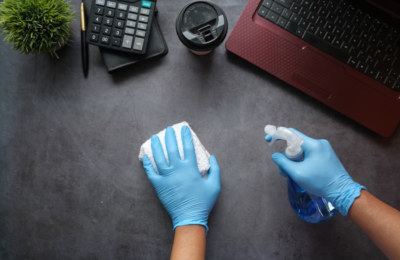 Profissional higienizando superfície com luvas e borrifador